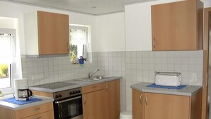 A compact kitchen with wooden cabinets, a built-in oven, a coffee maker, and a toaster. - Apartment Hug - Apartment, 4 bedrooms, from 5 persons, max. 7 people (Ringsheim)