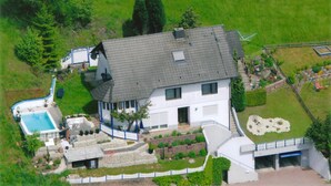 Eine Luftaufnahme eines Hauses mit Swimmingpool, umzäunter Garten und kleinem Gemüsegarten.