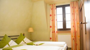 Une chambre d’hôtel avec deux lits, une fenêtre avec des rideaux, une lampe et un radiateur.