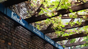 Een bord met de woorden 'fabrik', 'kino', 'kneipe' en 'galerie' op een houten constructie.