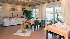 Un coin repas avec une table dressée pour quatre personnes, une grande plante et une vue sur l’extérieur.
