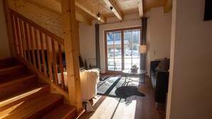 A wooden staircase leading to a living area with a sofa, a lamp, and a view of the outdoors.