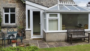 A stone house with a conservatory, a door, and a bench. - 3 bedroom accommodation in Arnside, near Grange-over-Sands (Arnside, near Grange-over-Sands)
