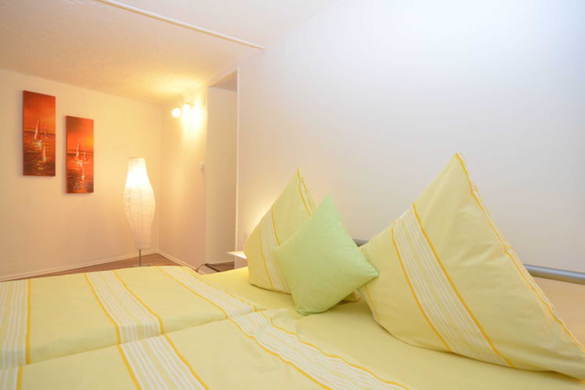 Una camera d'albergo con un letto, cuscini, una lampada e decorazioni alle pareti.