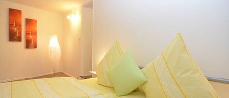 Una camera d'albergo con un letto, cuscini, una lampada e decorazioni alle pareti.