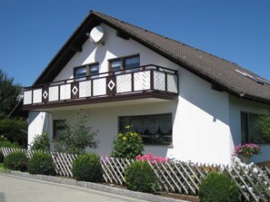 A two-story house with a balcony, white exterior walls, and a brown roof. - Haus Rehblick - Apartment 77sqm, 2 bedrooms, max. 5 people (Bräunlingen)