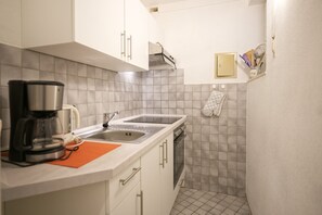 A compact kitchen with a coffee maker, a sink, and a dishwasher.
