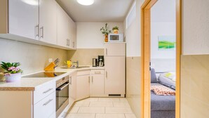Cocina compacta con microondas, cafetera y una pequeña planta en maceta.