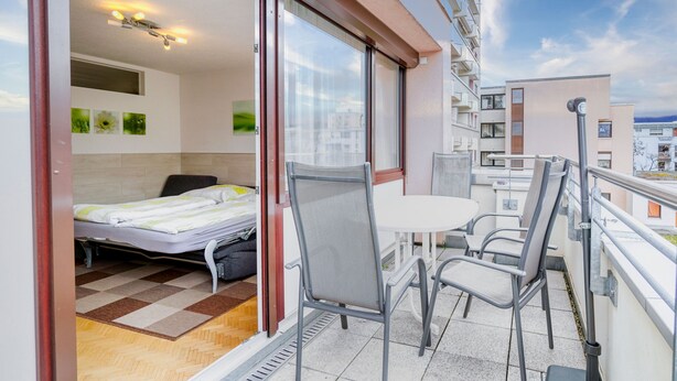 Un balcón con cama, una mesa y sillas.