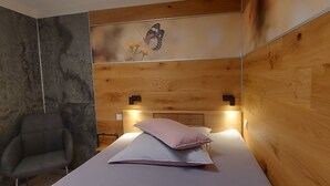 Una habitación con una cama, una silla, un muro de madera y una obra de arte con mariposas.