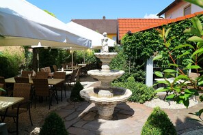 Un patio con una fuente de piedra, asientos exteriores y sombrillas.