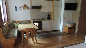 A compact kitchen with a dining area, a sofa, and a television.