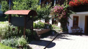A rustic building with a garden area, a wooden bench, and a mailbox.