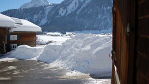 A snowy mountain landscape with a wooden building and a pile of snow in the foreground.
