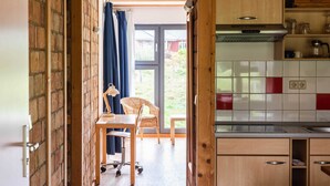 Een keuken met houten kastjes, een spoelbak en een raam met gordijnen.