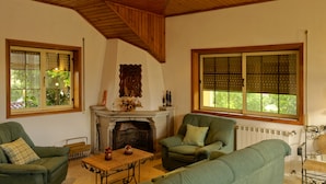 A cozy living room with a fireplace, green sofas, and large windows. - Zen Vouga - Quinta do Fundo de Vila (Oliveira de Frades)
