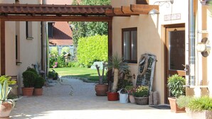 A reception area with a sign, potted plants, and a wooden pergola. - Two-Bedroom Apartment (4) - Pension Vanii (Rust)