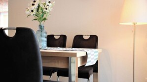 Un coin repas comprenant une table, des chaises, un vase avec des fleurs, une horloge et une lampe.