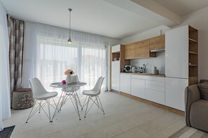 A modern kitchen with white cabinets, a wooden countertop, and a dining area with a round table and two chairs. - Villa Compass Luxury in a natural bay (Rogoznica)