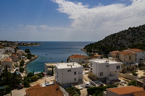 A coastal residential area with white buildings, a clear blue sea, and a hilly backdrop. - Villa Compass Luxury in a natural bay (Rogoznica)