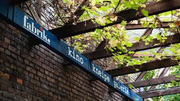 Ein Schild mit den Aufschriften 'Fabrik', 'Kino', 'Kneipe' und 'Galerie' an einer Holzkonstruktion.