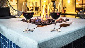 Duas taças de vinho sobre uma mesa, com uma lareira ao fundo.