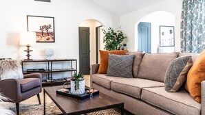Uma sala de estar moderna com sofá, poltrona, mesa de centro e objetos decorativos.