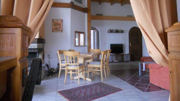 A room with a dining table, chairs, a TV, and a fireplace.