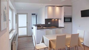 Una cocina moderna con armarios blancos, una isla central y un comedor con mesa y sillas.