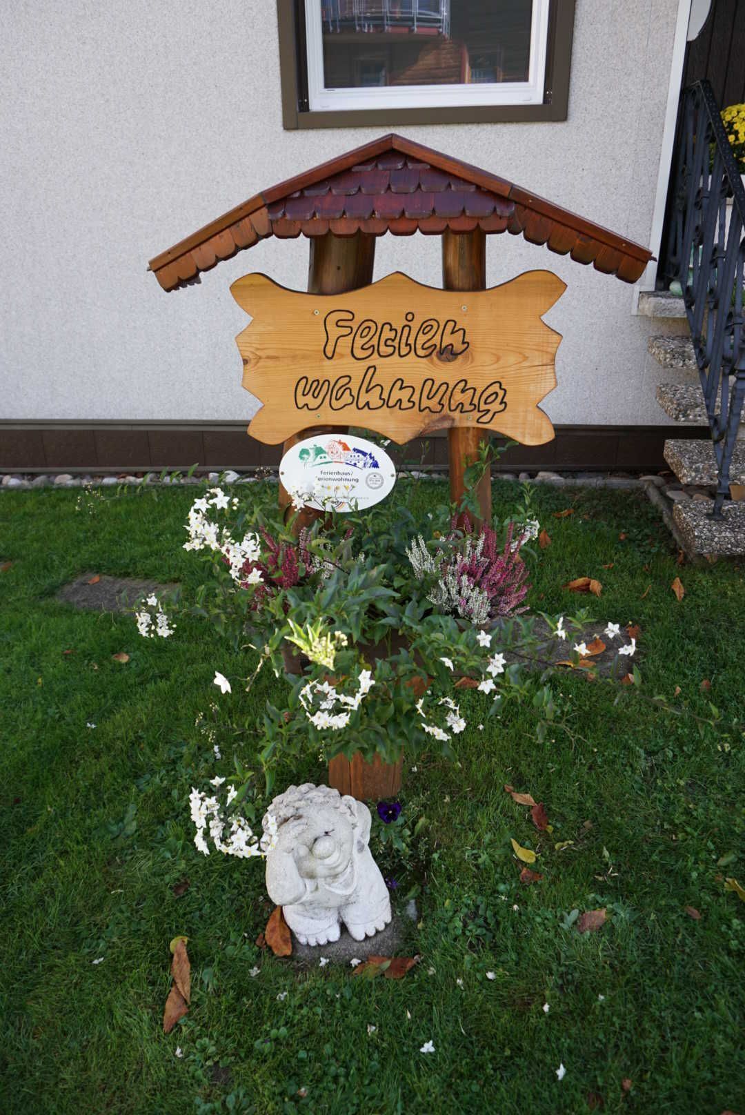 A wooden sign with the text "Fertig gemacht" in a garden setting.