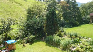 Un quartier résidentiel avec des maisons construites sur une colline, un jardin clôturé et une structure de jeu en bois.