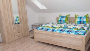 A bedroom with a wooden bed, a wardrobe, a mirror, and a skylight.