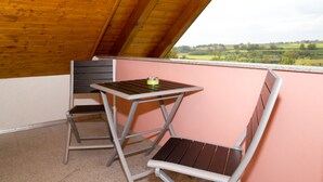 A balcony with a wooden ceiling, a table, and two chairs.