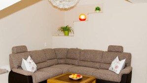 A modern living room with a sectional sofa, a wooden coffee table, and decorative plants on shelves.