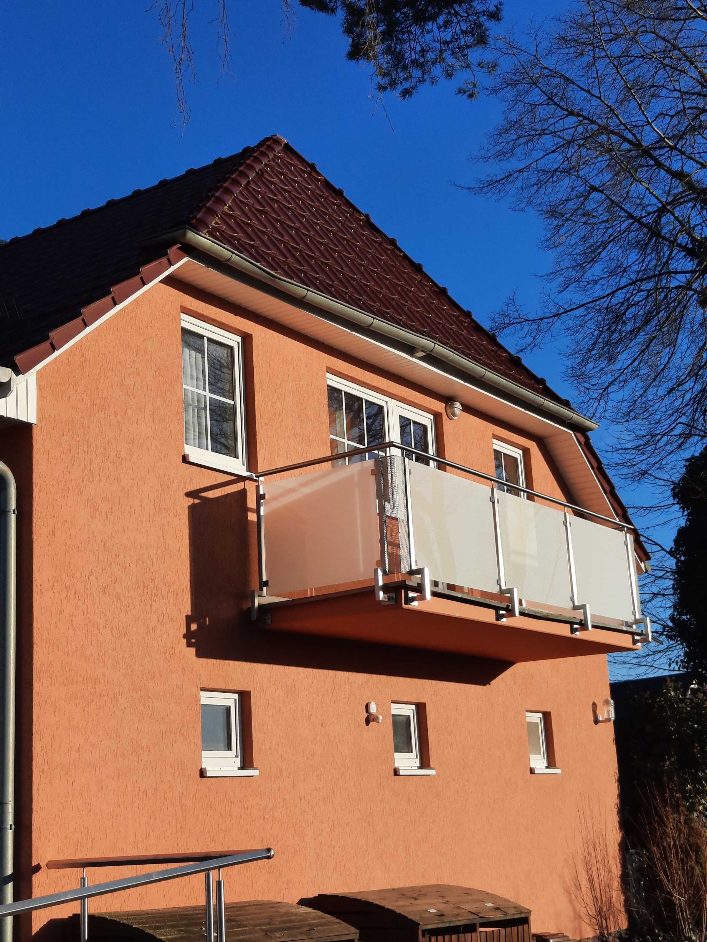 A two-story building with a brown facade, white window frames, and a red-tiled roof.