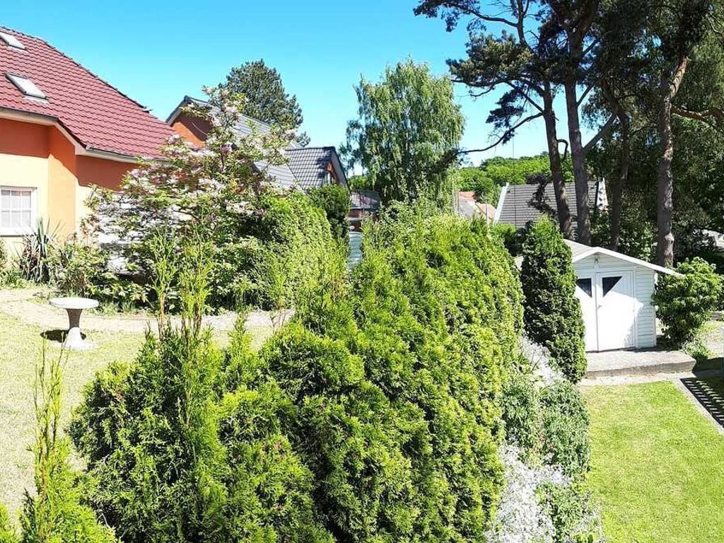 A residential area with a well-maintained lawn, a small shed, and houses with red roofs.