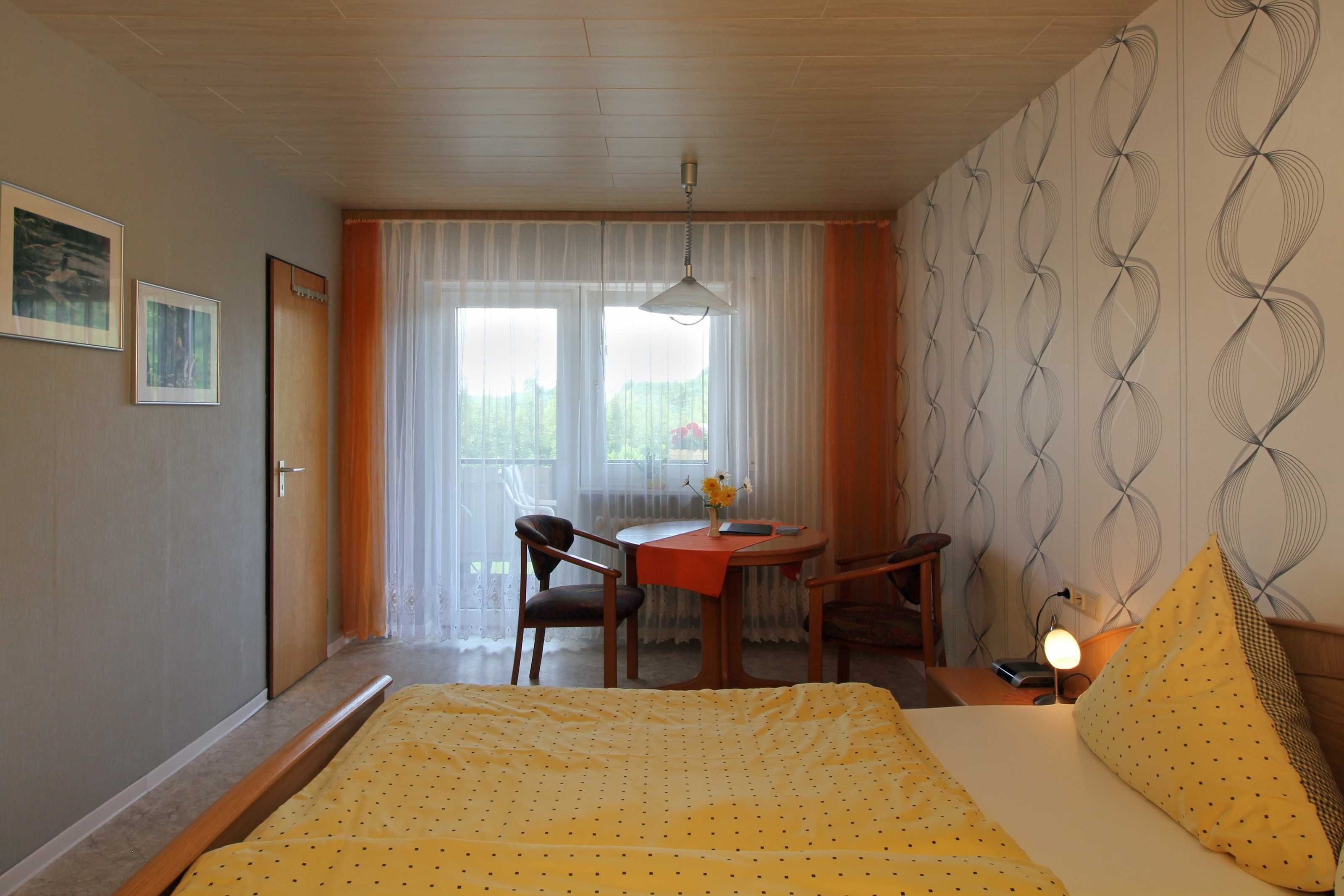Una camera da letto con un letto, un tavolo con sedie, una scrivania e una finestra con tende.