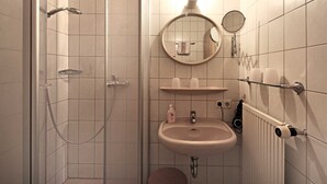 A bathroom with a shower, sink, mirror, towel rack, and toilet. - Double room blue - Winery Baumer (Vogtsburg im Kaiserstuhl)