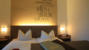 Een hotelkamer met een bed, twee nachtkastjes en een muur met een stadsreisaand thema.