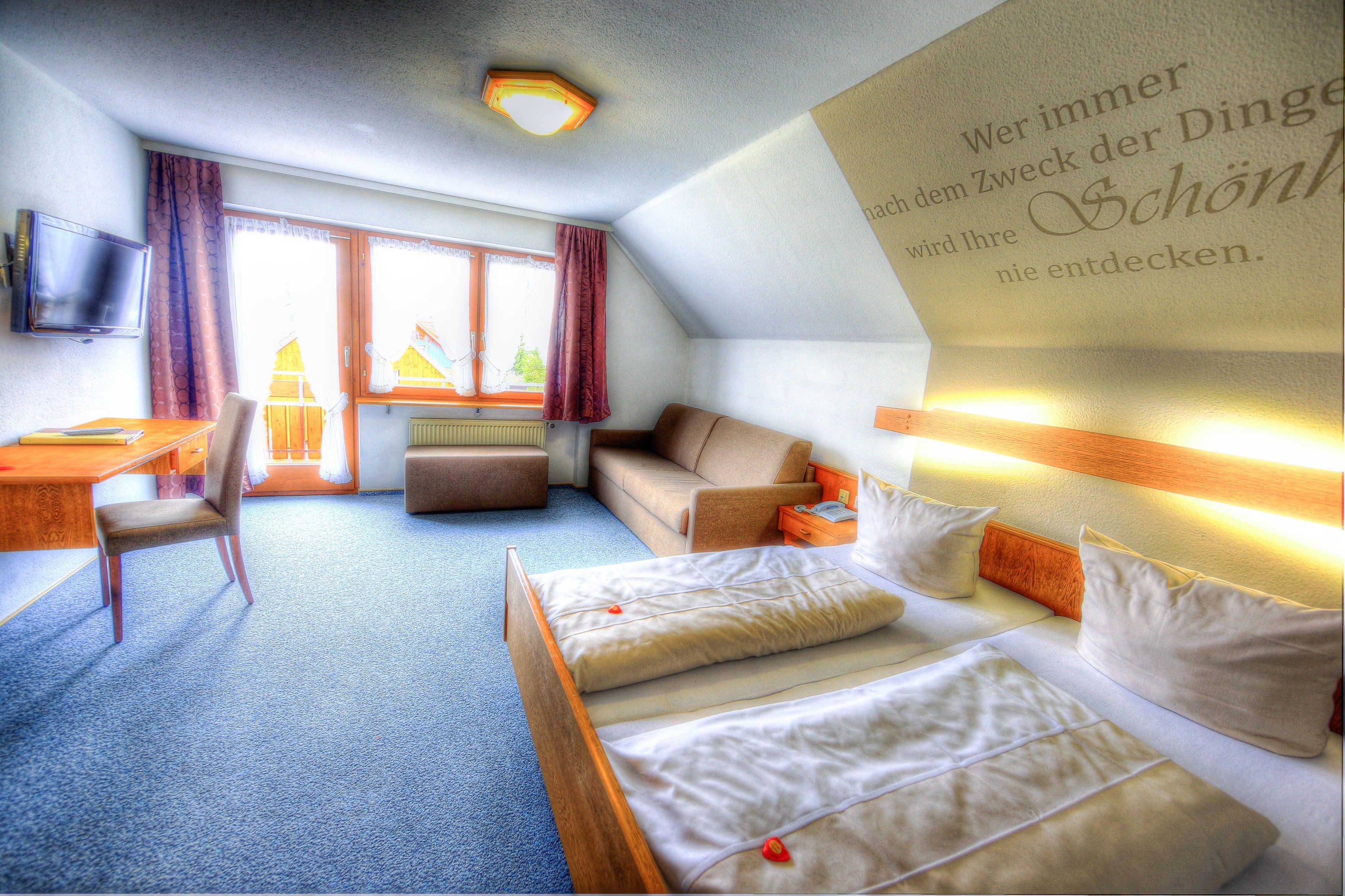 Une chambre d’hôtel équipée d’un lit, d’un bureau, d’une chaise, d’un canapé et d’une télévision.