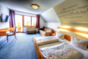 Une chambre d’hôtel équipée d’un lit, d’un bureau, d’une chaise, d’un canapé et d’une télévision.