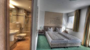 Une chambre d’hôtel avec une douche, des toilettes et un lit recouvert d’une moquette verte.