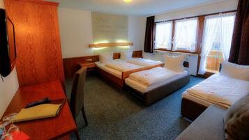 Une chambre d’hôtel avec deux lits, un bureau, une chaise et un téléviseur.