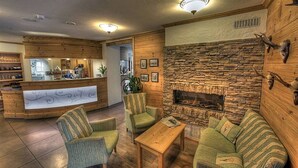 Een knusse lobby met een stenen openhaard, een houten receptiebalie en comfortabele zithoek.