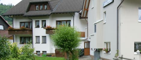 Un bâtiment à deux étages doté d’un balcon, d’un petit jardin et d’une clôture en bois.