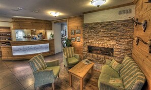 Een knusse lobby met een stenen openhaard, een houten receptiebalie en comfortabele zithoek.