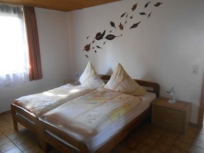 Una cama bien hecha con ropa de cama floral, un cabecero de madera y una mesita de noche con una lámpara.