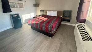Ein Hotelzimmer mit einem großen Bett, einer Mikrowelle, einem Heizkörper und einem Vorhangfenster.