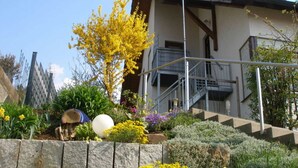 Un bâtiment moderne doté d’un mur de soutènement en pierre, d’un escalier et d’une variété de plantes et de fleurs.