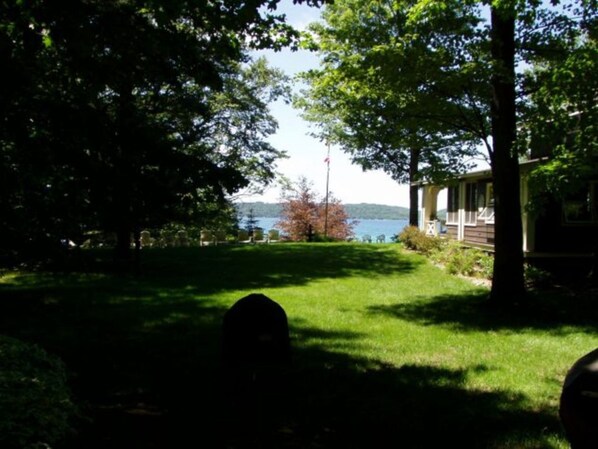 A view of a house with a lawn and a body of water in the background.